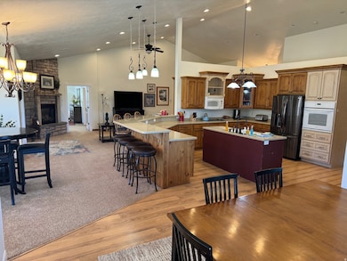 Kitchen with a chandelier, white appliances, a breakfast bar area, hanging light fixtures, and high vaulted ceiling