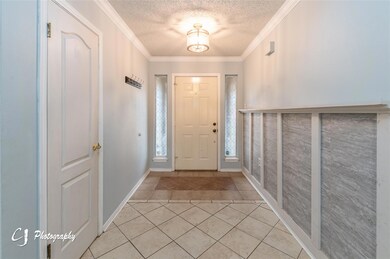 Tiled foyer featuring crown molding and a textured