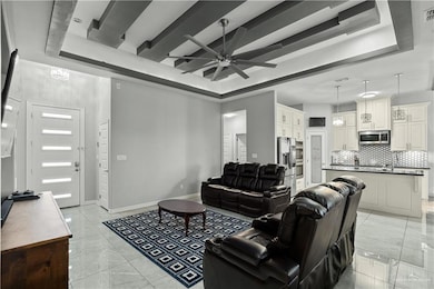 Living area featuring a tray ceiling, ceiling fan, and light tile patterned flooring