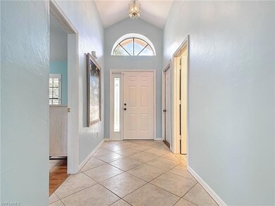 Foyer entrance featuring lofted ceiling, light tile patterned flooring, plenty of natural light, baseboards, and a textured wall