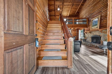 Stairway with rustic walls, wood finished floors, a fireplace, high vaulted ceiling, and wood ceiling