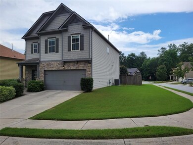 View of front of house featuring stone siding, an attached garage, a front lawn, and driveway