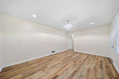 Unfurnished room featuring a chandelier and light wood-type flooring