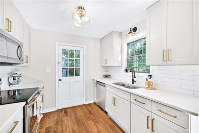Kitchen with decorative backsplash, appliances with stainless steel finishes, light wood-style flooring, white cabinetry, and a textured ceiling