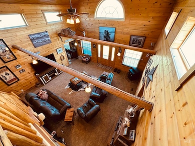 Living area featuring a towering ceiling, wooden walls, wood ceiling, and a ceiling fan