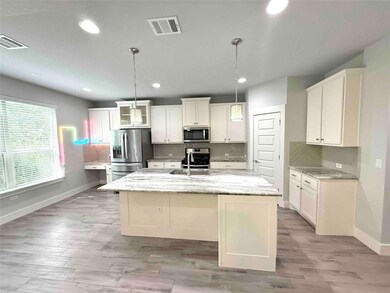 Kitchen with light stone countertops, decorative backsplash, appliances with stainless steel finishes, white cabinetry, and recessed lighting