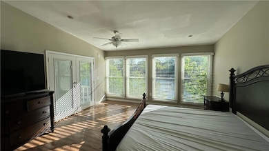 Bedroom with a ceiling fan, multiple windows, wood