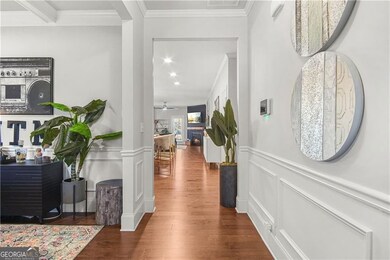 Hallway featuring ornamental molding, ornate columns, and dark wood-type flooring