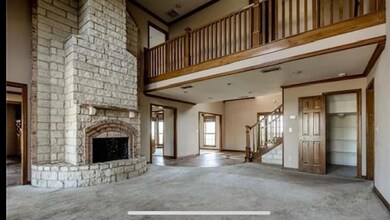 Unfurnished living room with carpet flooring, brick wall, a large fireplace, crown molding, and a high ceiling
