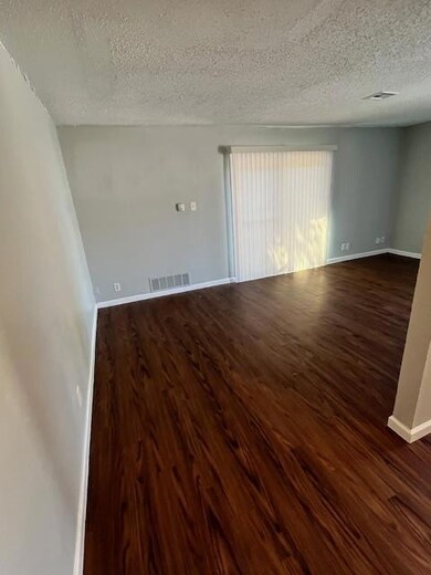 Spare room featuring a textured ceiling and dark wood-style floors