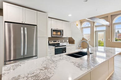 Kitchen featuring light wood-type flooring, appliances with stainless steel finishes, a healthy amount of sunlight, and sink