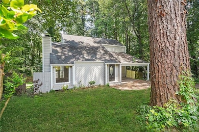 Rear view of property with a chimney, a shingled roof, and a patio area