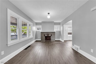 Unfurnished living room with dark wood-type flooring and a brick fireplace