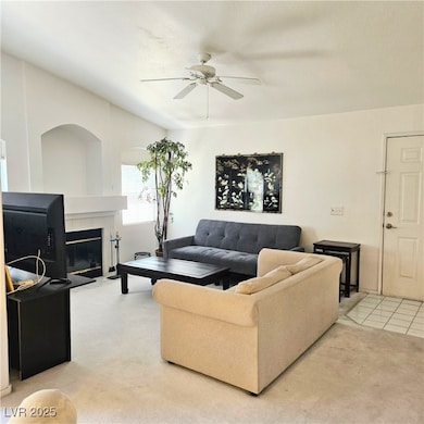 Living area with ceiling fan, light carpet, and a