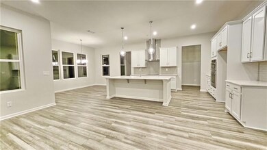 Kitchen featuring wall chimney range hood, tasteful backsplash, recessed lighting, light countertops, and stainless steel double oven