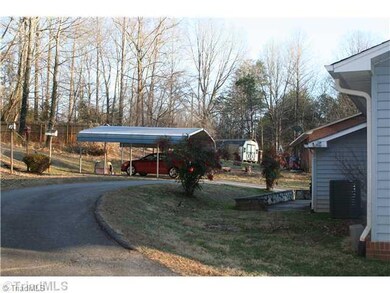 Exterior Back. Circle driveway with 2 car carport.  Paved area in back perfect for grilling out