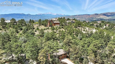 Aerial view of the front of the home, mountain range, and Pikes Peak.