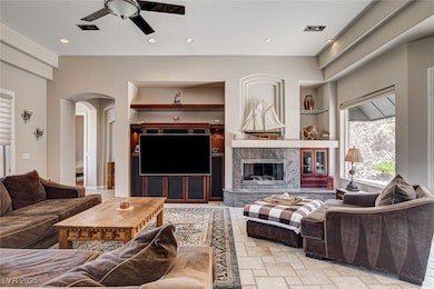 Living area with ceiling fan, built in features, a