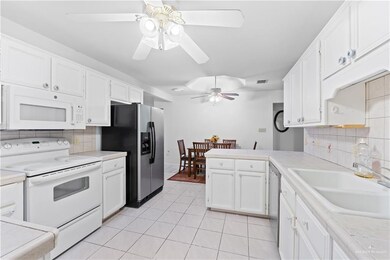 Kitchen with backsplash, stainless steel appliances, ceiling fan, sink, and white cabinets