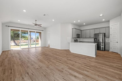 Kitchen featuring open floor plan, gray cabinetry, stainless steel appliances, recessed lighting, and light wood-style flooring