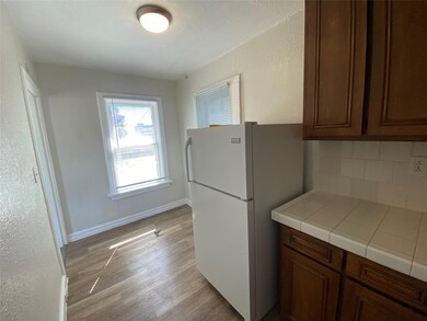 Kitchen with dark brown cabinets, tasteful backsplash, light hardwood / wood-style flooring, and white refrigerator