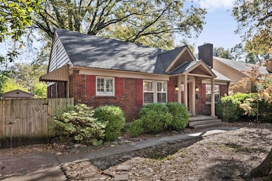 View of front facade featuring brick siding, a chimney, and a shingled roof