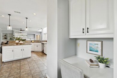 Kitchen featuring hanging light fixtures, white cabinets, light stone countertops, light tile flooring, and dishwasher