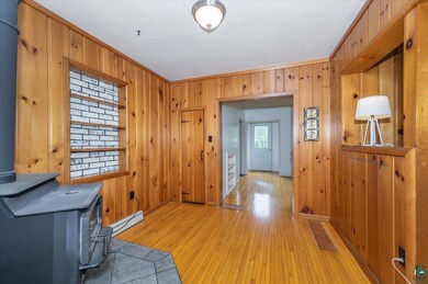 Foyer featuring wooden walls, light wood-type flooring, a baseboard heating unit, and ornamental molding