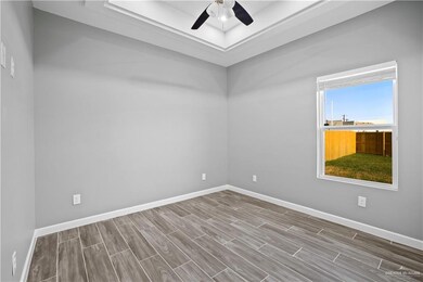 Empty room featuring baseboards, wood tiled floor, ceiling fan, and a tray ceiling