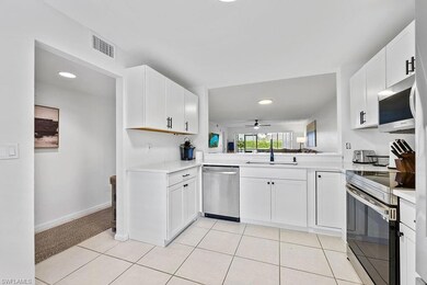 Kitchen featuring light tile patterned floors, stainless steel appliances, light countertops, white cabinetry, and a sink