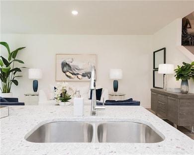 Kitchen with light stone counters, recessed lighting, and open floor plan