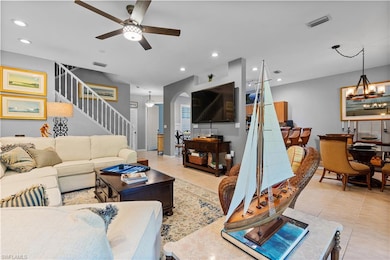 Living area featuring stairway, ceiling fan with notable chandelier, light tile patterned floors, visible vents, and recessed lighting