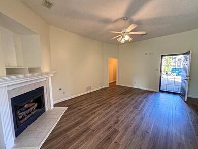 Unfurnished living room with a textured ceiling, wood finished floors, a ceiling fan, a fireplace, and baseboards