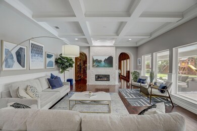Stunning Living room featuring beamed/coffered ceiling, projector screen, and two-way stone fireplace, opening to Library