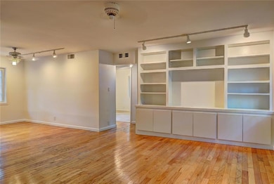 Spare room featuring rail lighting, a ceiling fan, hardwood / wood-style flooring, and baseboards