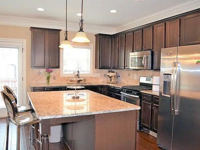 Kitchen with light stone counters, dark brown cabinetry, dark wood-style floors, and stainless steel appliances