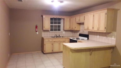 Kitchen with white electric stove, a peninsula, tasteful backsplash, and light countertops