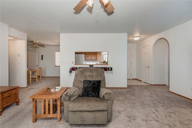 Living area featuring a ceiling fan, light carpet,
