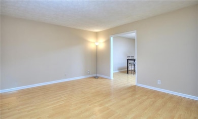 Unfurnished room featuring light wood-style floors, baseboards, and a textured ceiling