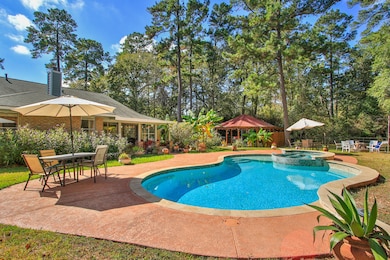 Large, inviting pool and attached spa, surrounded by lush greenery.