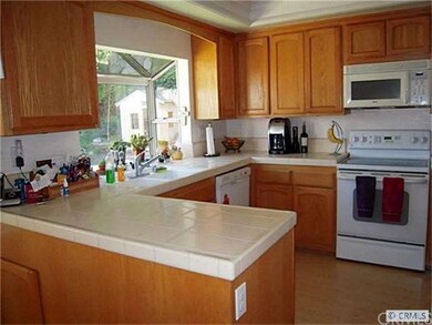 The sunny kitchen features a tile counter, gleamin
