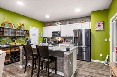 Kitchen featuring stainless steel appliances, wood finished floors, white cabinetry, baseboards, and recessed lighting