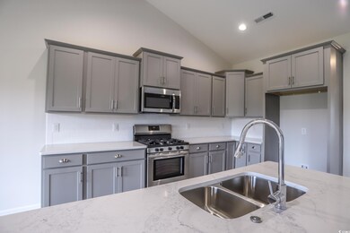 Kitchen featuring lofted ceiling, light stone coun