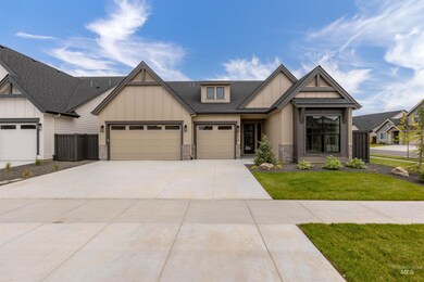 View of front facade featuring board and batten siding, roof with shingles, driveway, an attached garage, and stone siding