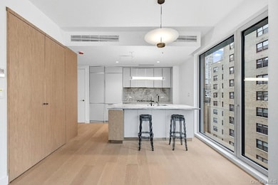 Kitchen with modern cabinets, a breakfast bar area, pendant lighting, light wood finished floors, and backsplash
