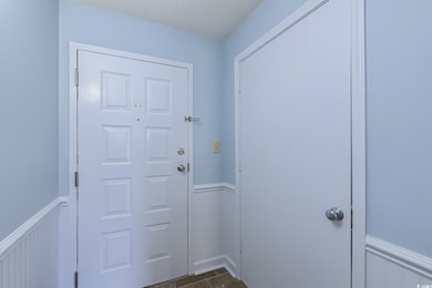 Doorway to outside with a wainscoted wall and tile patterned flooring