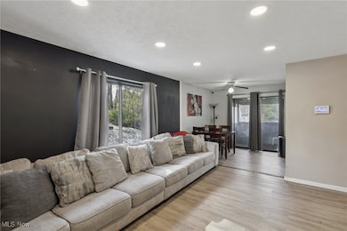 Living area with healthy amount of natural light, wood finished floors, recessed lighting, a textured ceiling, and a ceiling fan