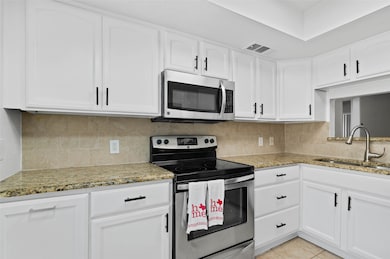 Modern kitchen with granite counter tops, decorative backsplash, and stainless appliances.
