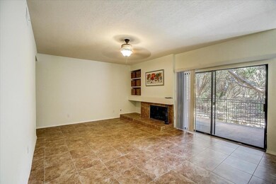 Unfurnished living room with a textured ceiling, a fireplace with raised hearth, and ceiling fan