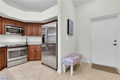 Kitchen with stainless steel appliances, light tile patterned floors, and light stone counters
